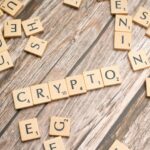 Wooden letter tiles spelling 'Crypto' creatively arranged on a rustic wood surface.